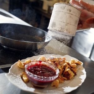 hausgemachter Kaiserschmarn mit Zwetschkenröster,der gerade mit Staubzucker verfeinert wird