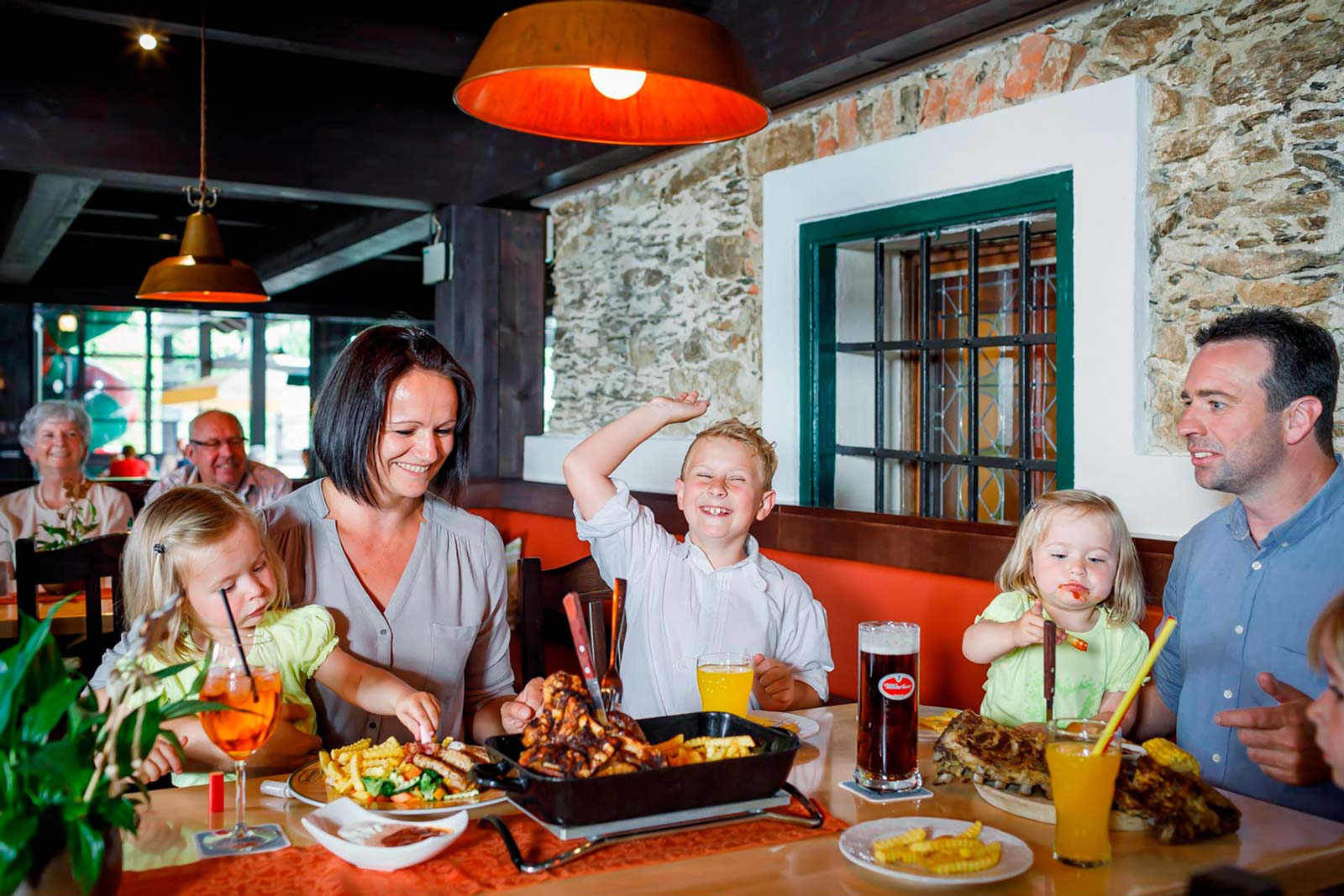 Familie mit kleinen Kindern sitzen am Tisch und Essen alle zusammen. Alle Lachen und haben eine gute Zeit.